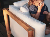 A child playing on a Neighbor teak outdoor sofa