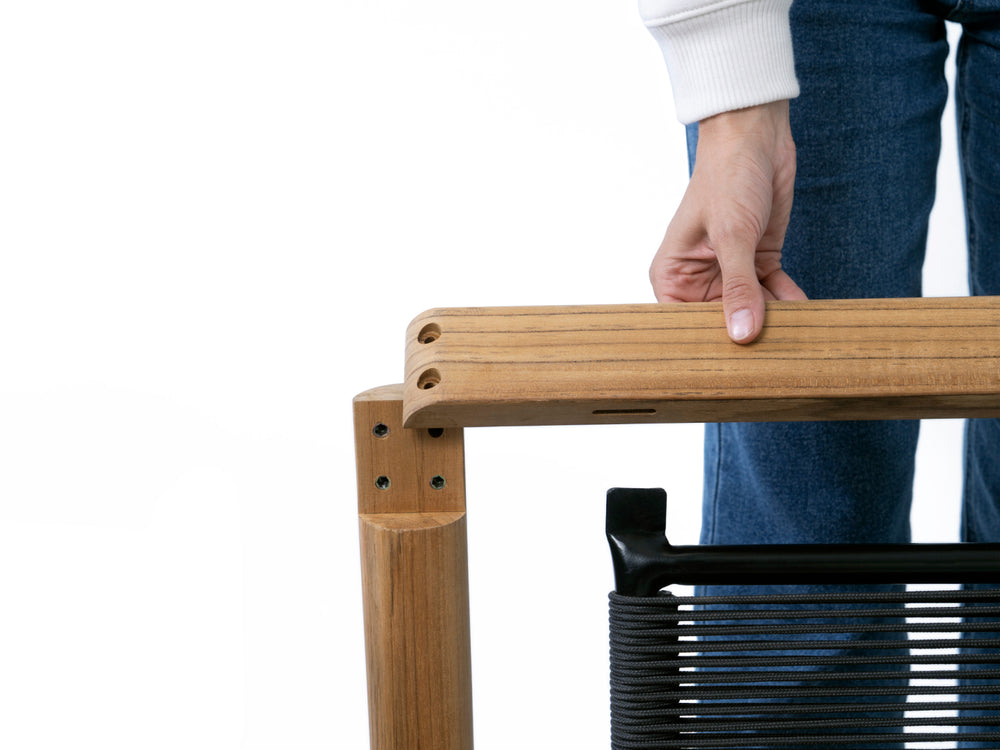 A person assembling a Neighbor teak furniture frame in the studio