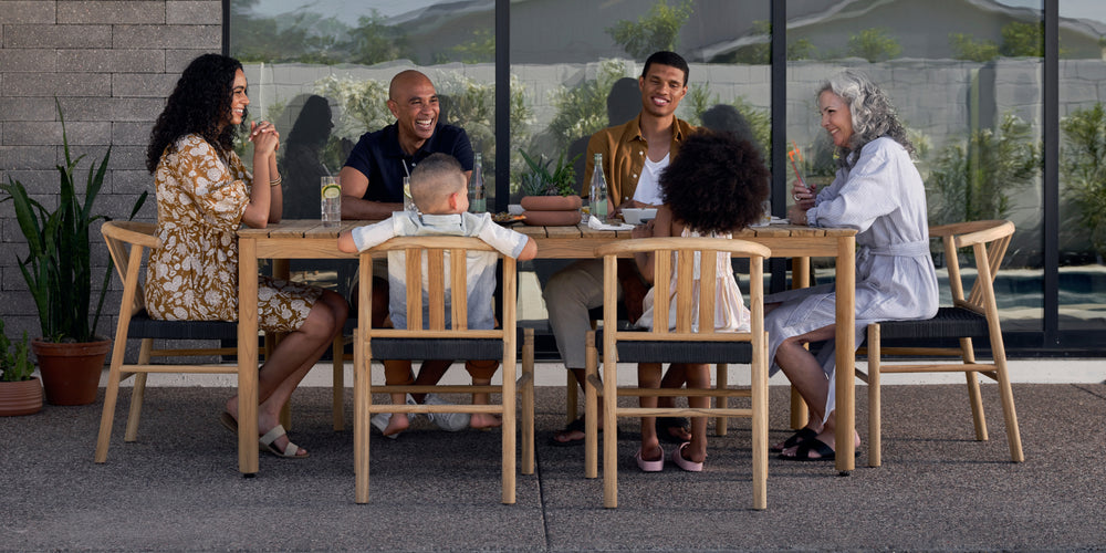 A family enjoying a meal around their Neighbor teak outdoor dining set