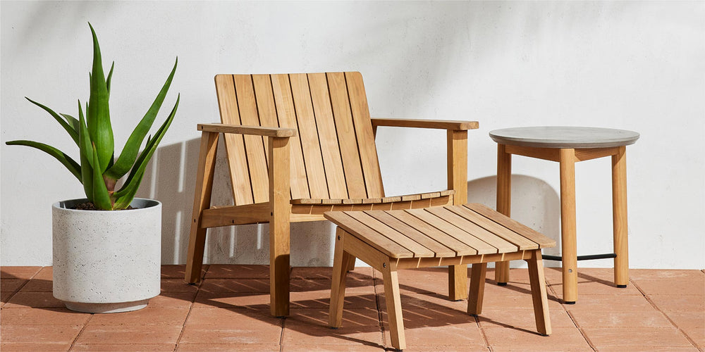 A Neighbor teak Low Chair and ottoman resting on a sunny patio.