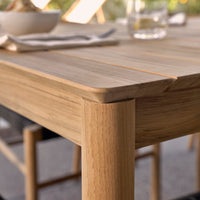 A low angle detail shot of a Neighbor teak outdoor dining table