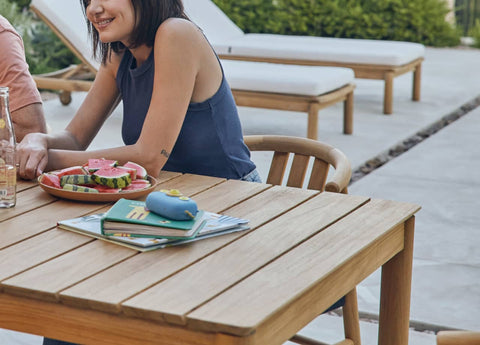 Teak outdoor dining set with teak sun loungers in background